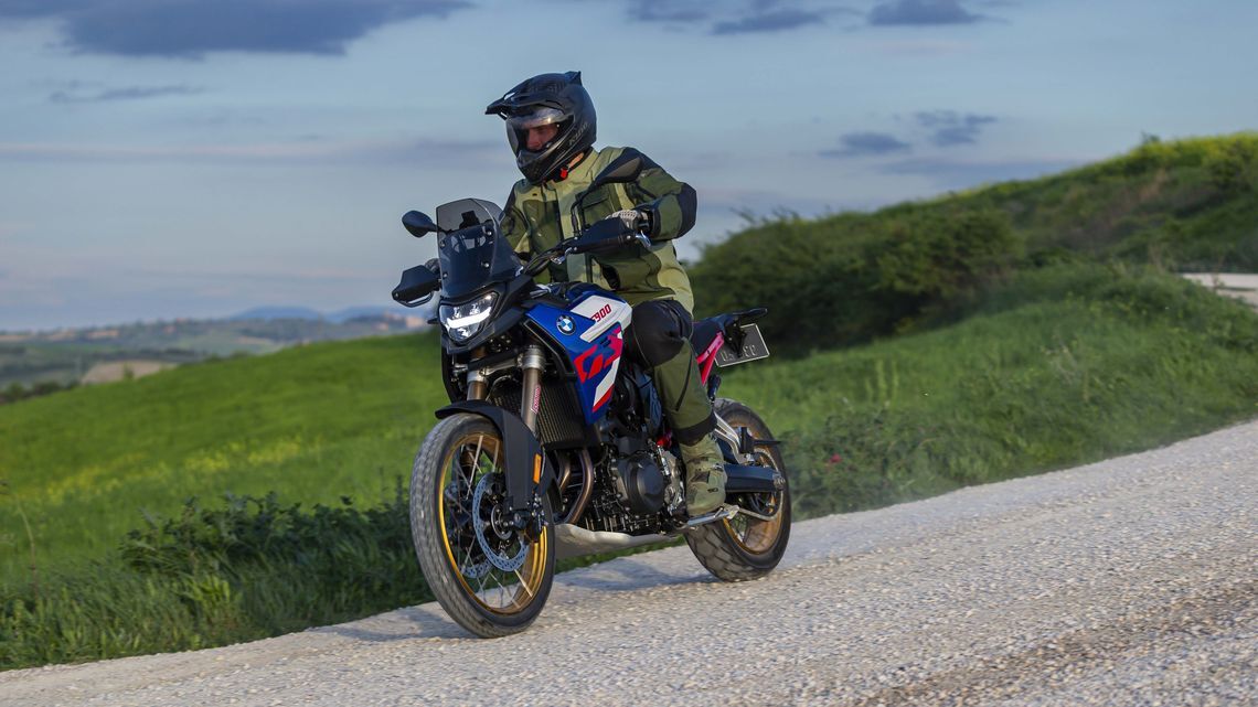 A rider on a BMW adventure motorbike navigating a dirt road with MICHELIN Anakee Adventure 2 tyres.