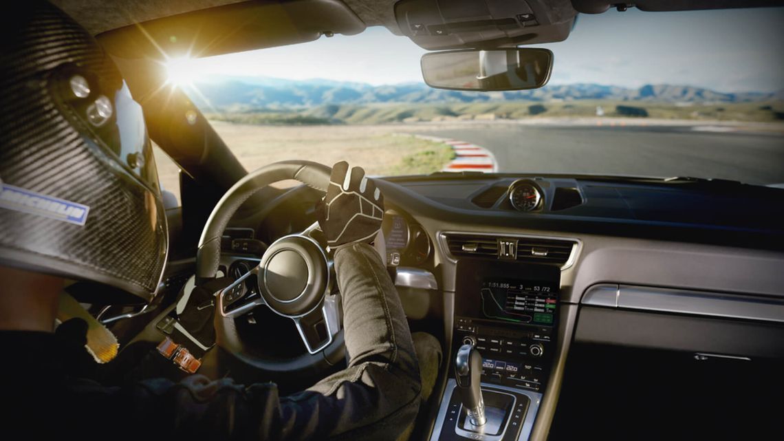 A person driving a sleek car on a winding road, focused on speed and precision during a weekend race.