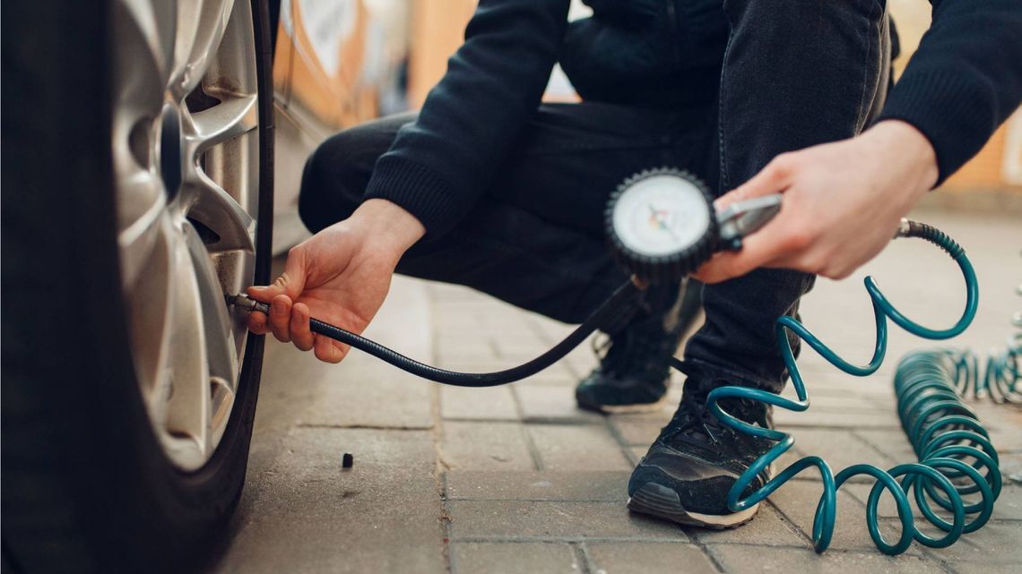 タイヤの空気圧をチェックする男性。自動車修理サービスまたはビジネス、男性が屋外で自動車のホイールに空気を入れる