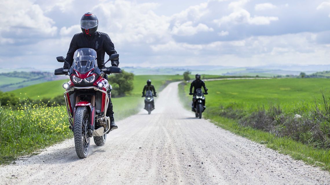 Three riders on adventure motorbikes travelling down a gravel road with MICHELIN Anakee Adventure 2 tyres.