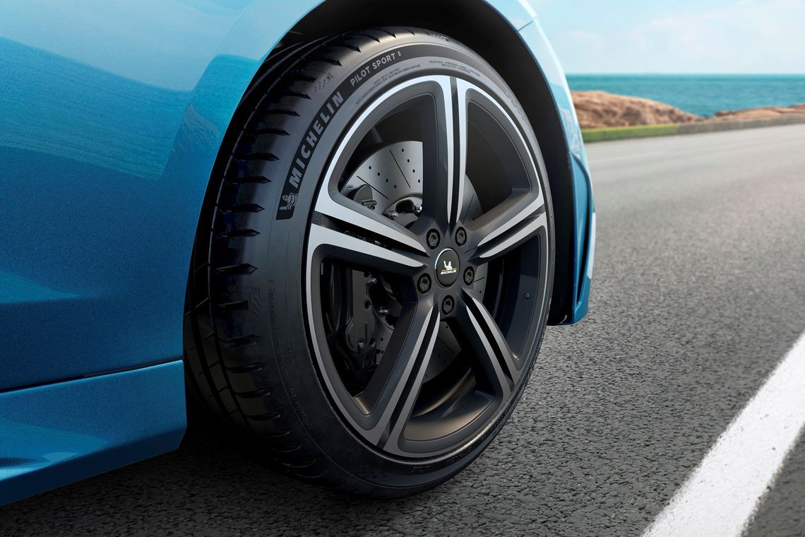 Close-up of the Pilot Sport 5 tyre on an urban road at night with skyscrapers in the back.