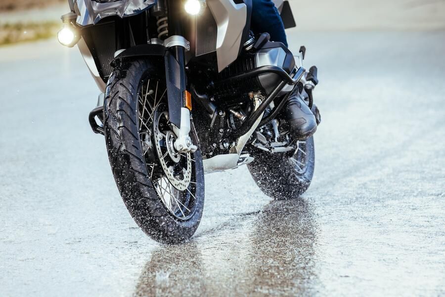 MICHELIN Anakee Road 2023 motorcycle tyre performing on wet pavement, showing water spray and tread contact with the road.