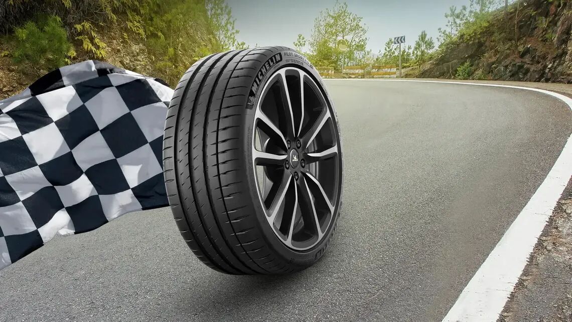 Michelin tyre rolling down the road with a black-and-white checkered flag on the left-hand side.