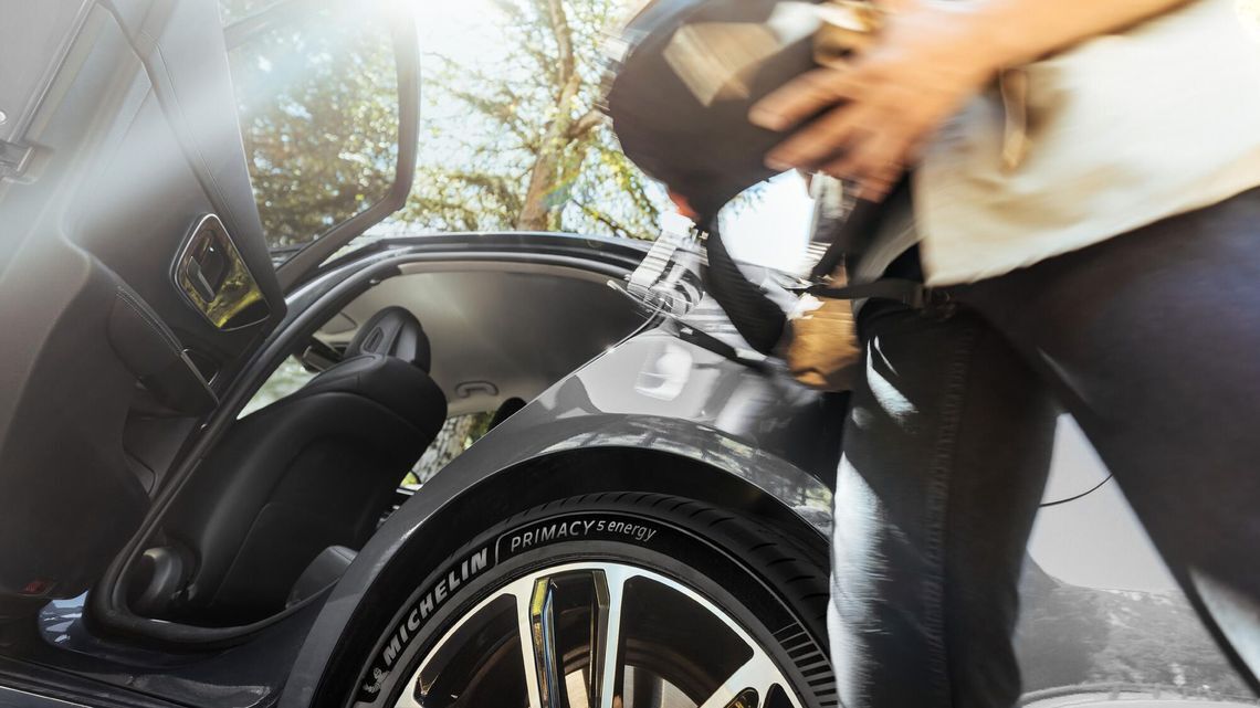 Close-up of a MICHELIN Primacy 5 Energy tyre on a car as a person packs a bag.