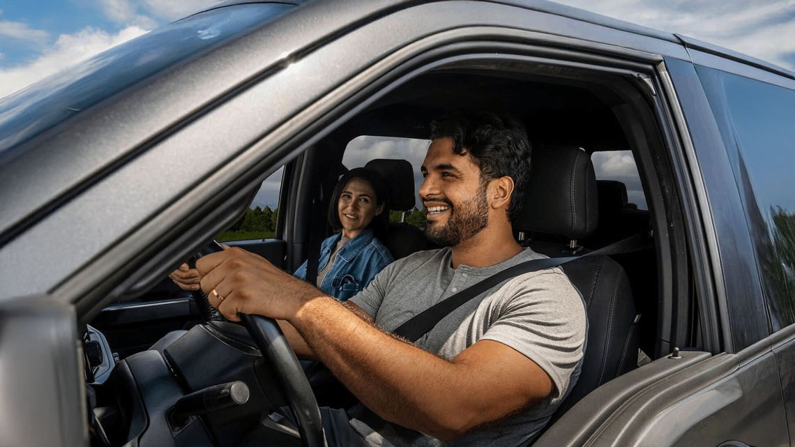 A smiling man and woman enjoy a drive together, embodying the joy of exploring their unique driving personalities.