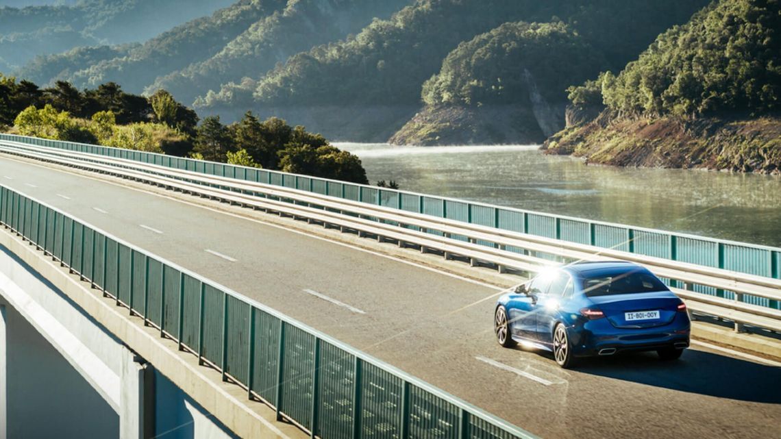 Une voiture traverse un pont au-dessus d'une rivière, incarnant l'aventure et la spontanéité lors d'un voyage pittoresque.