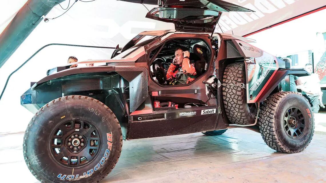 Offroad-tävlingsbil med öppna dörrar visar insidan av bilen och föraren, utrustade med BFGoodrich-däck och säkerhetssele, under ett tält vid en biltävling