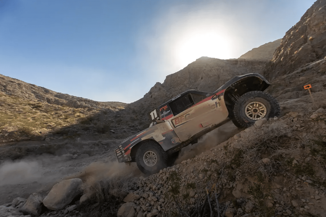 BFGoodrich terrängtävlingslastbil klättrar uppför en stup, stenig sluttning under Mint 400 ökentävling under blåa skyar