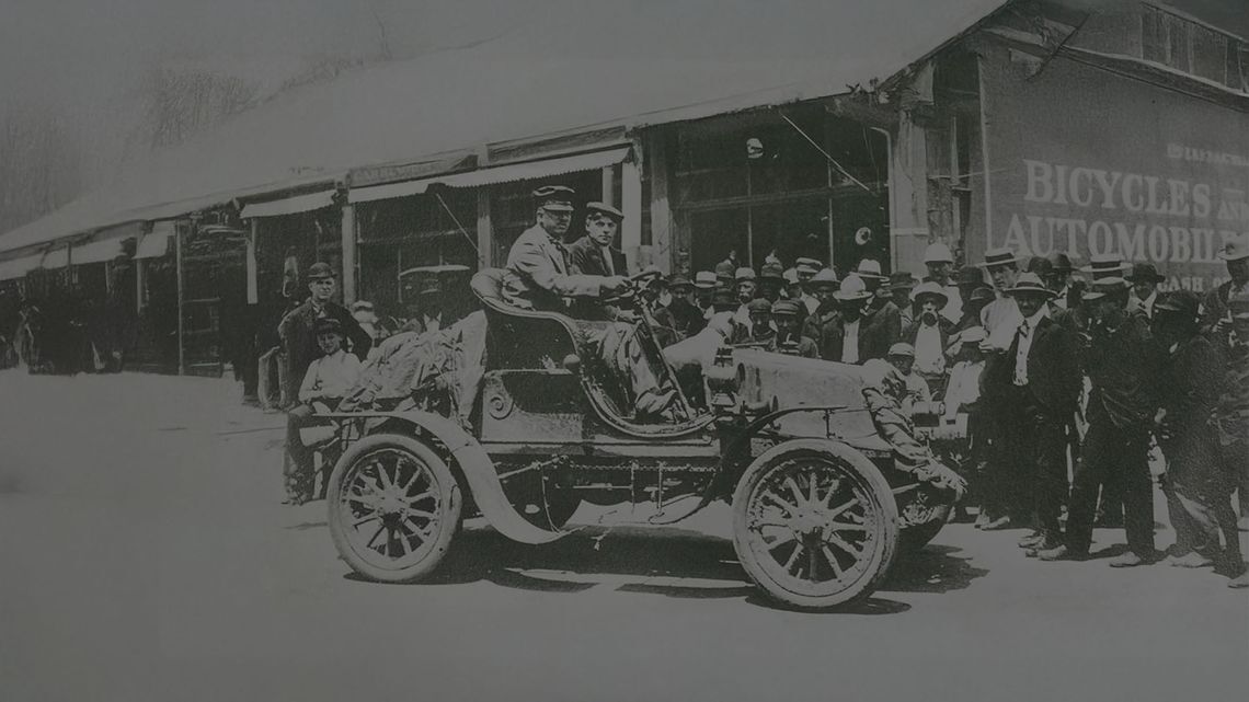 Voiture ancienne devant un garage historique, illustration vintage de l'histoire automobile avec pneus BFG