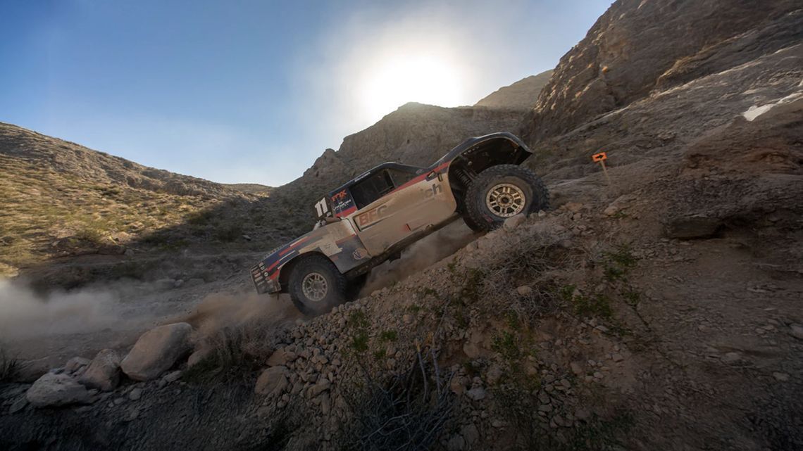 Il camion da offroad BFGoodrich si arrampica su un ripido pendio roccioso durante la gara nel deserto Mint 400, sotto un cielo azzurro