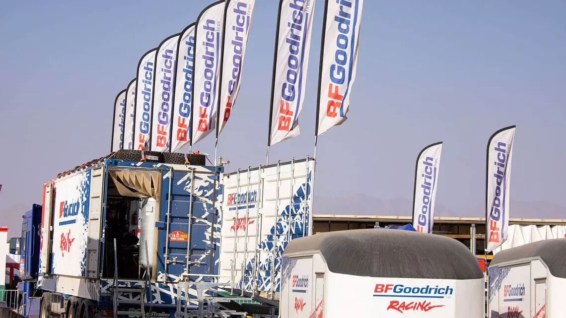 "BFGoodrich-tävlingsevent i öknen med flera flaggor och lastbilar i varumärkets färger "