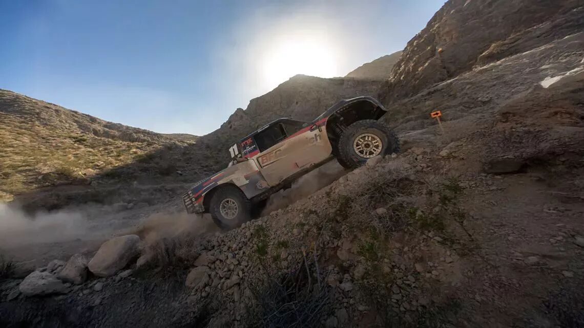 Camión de carreras todoterreno BFGoodrich subiendo una pronunciada pendiente rocosa durante la carrera desértica Mint 400 bajo un cielo azul