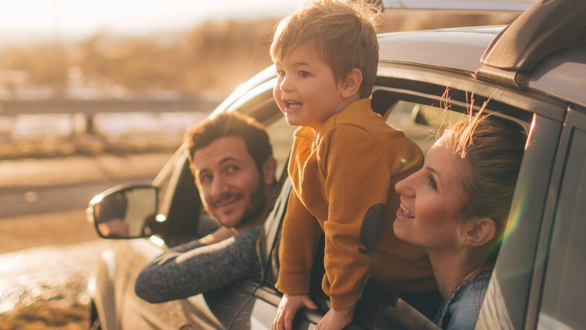 A man, a woman and a child standing at a car window